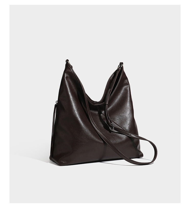 Large slouchy hobo shoulder bag with braided top handle, smooth glossy leather-look finish, and silver-tone ring hardware