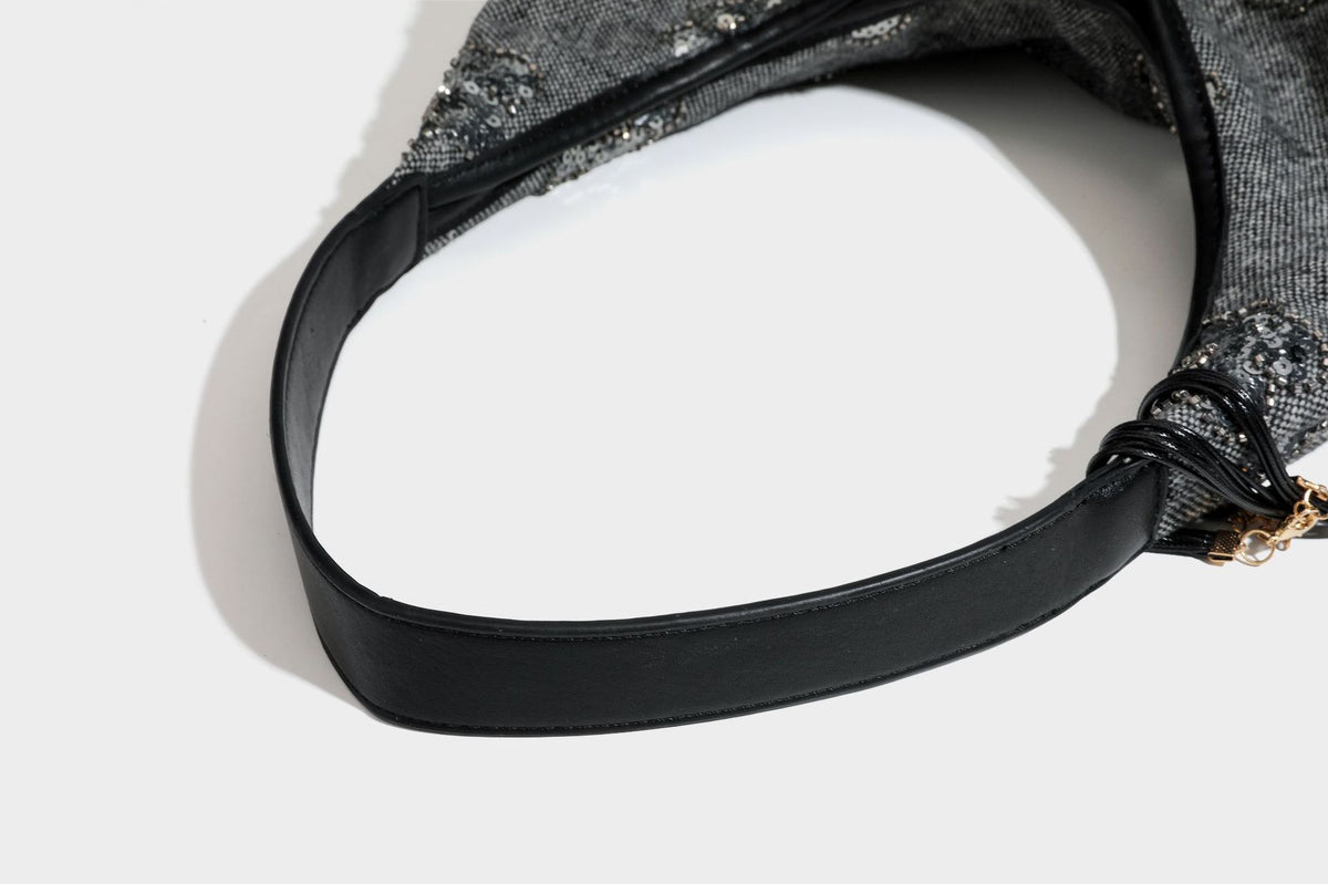 Lässig fallende, trapezförmige Schulter-Tote in Anthrazitgrau mit floralen Paillettenmotiven in Silber, Riemen in Lederoptik und herabhängendem Perlenbesatz