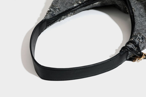 Lässig fallende, trapezförmige Schulter-Tote in Anthrazitgrau mit floralen Paillettenmotiven in Silber, Riemen in Lederoptik und herabhängendem Perlenbesatz