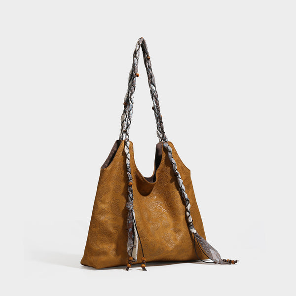 Slouchy paisley-embossed suede-look shoulder tote bag with braided patterned fabric straps and wood bead accents, detail view