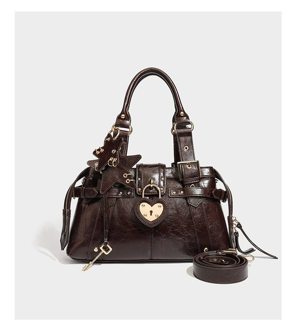 Structured leather-look satchel bag with heart padlock charm, star charm, gold-tone buckle hardware, dual top handles, and