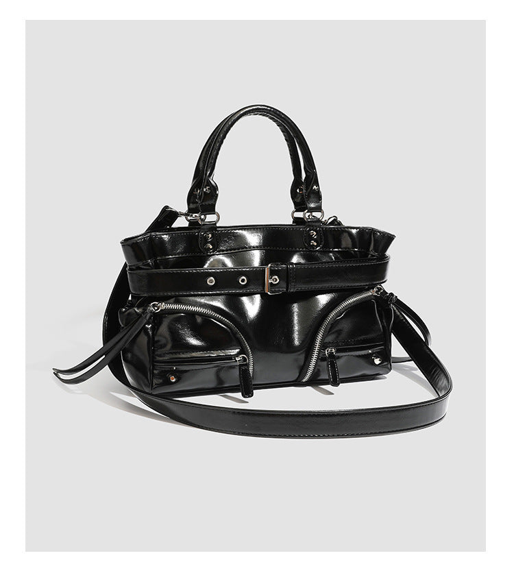 Black glossy structured tote bag with rivet and buckle detail, dual top handles, and detachable shoulder strap, detail view 8