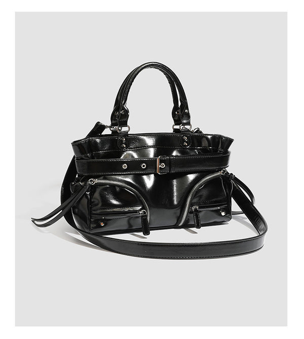 Black glossy structured tote bag with rivet and buckle detail, dual top handles, and detachable shoulder strap, detail view 8