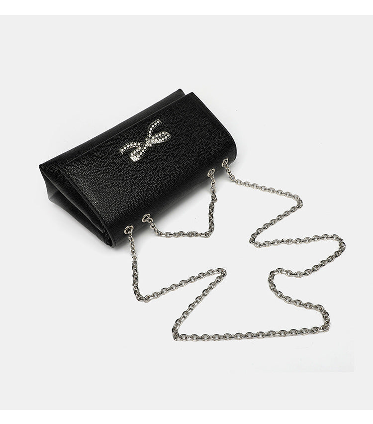 Structured rectangular flap crossbody bag with rhinestone bow and silver chain strap in pebbled finish, detail view 11