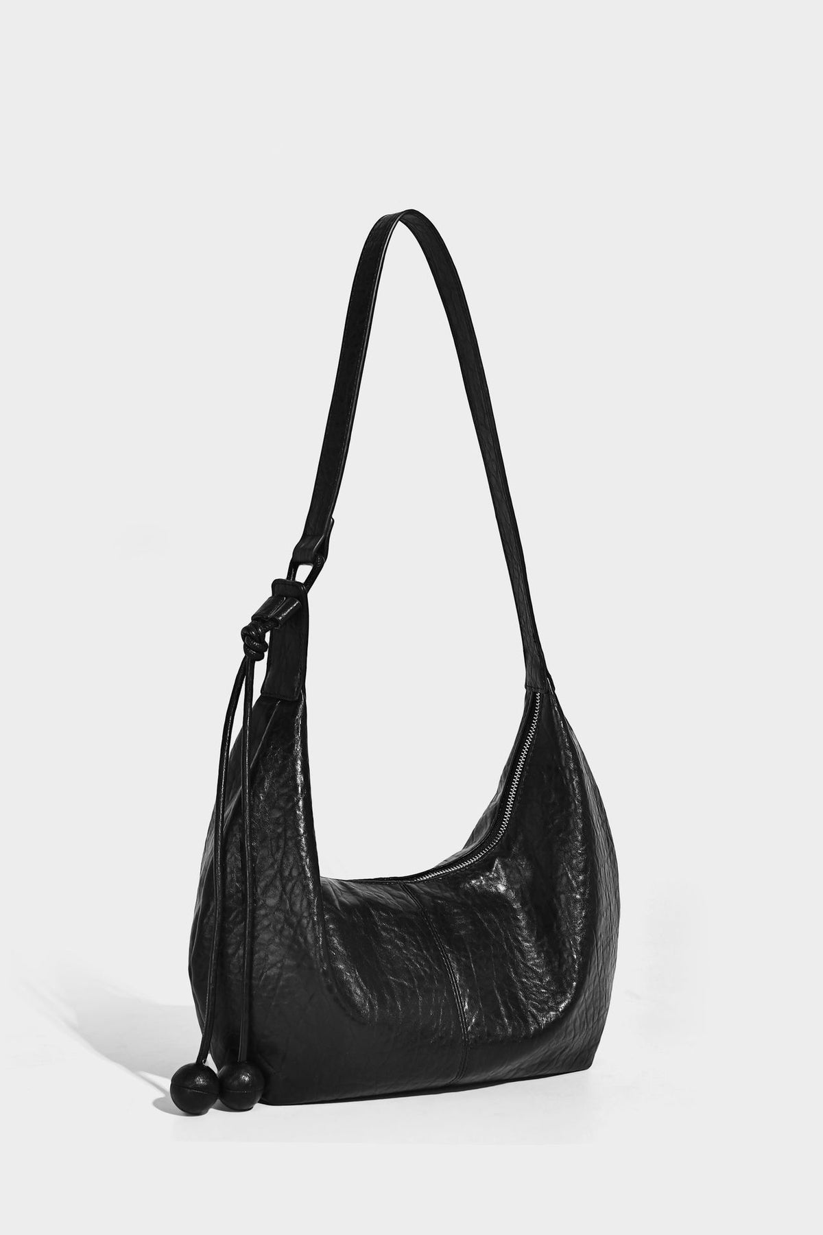 Slouchy crescent half-moon shoulder bag in pink pebbled textured finish with floral charm and knotted side detail, detail