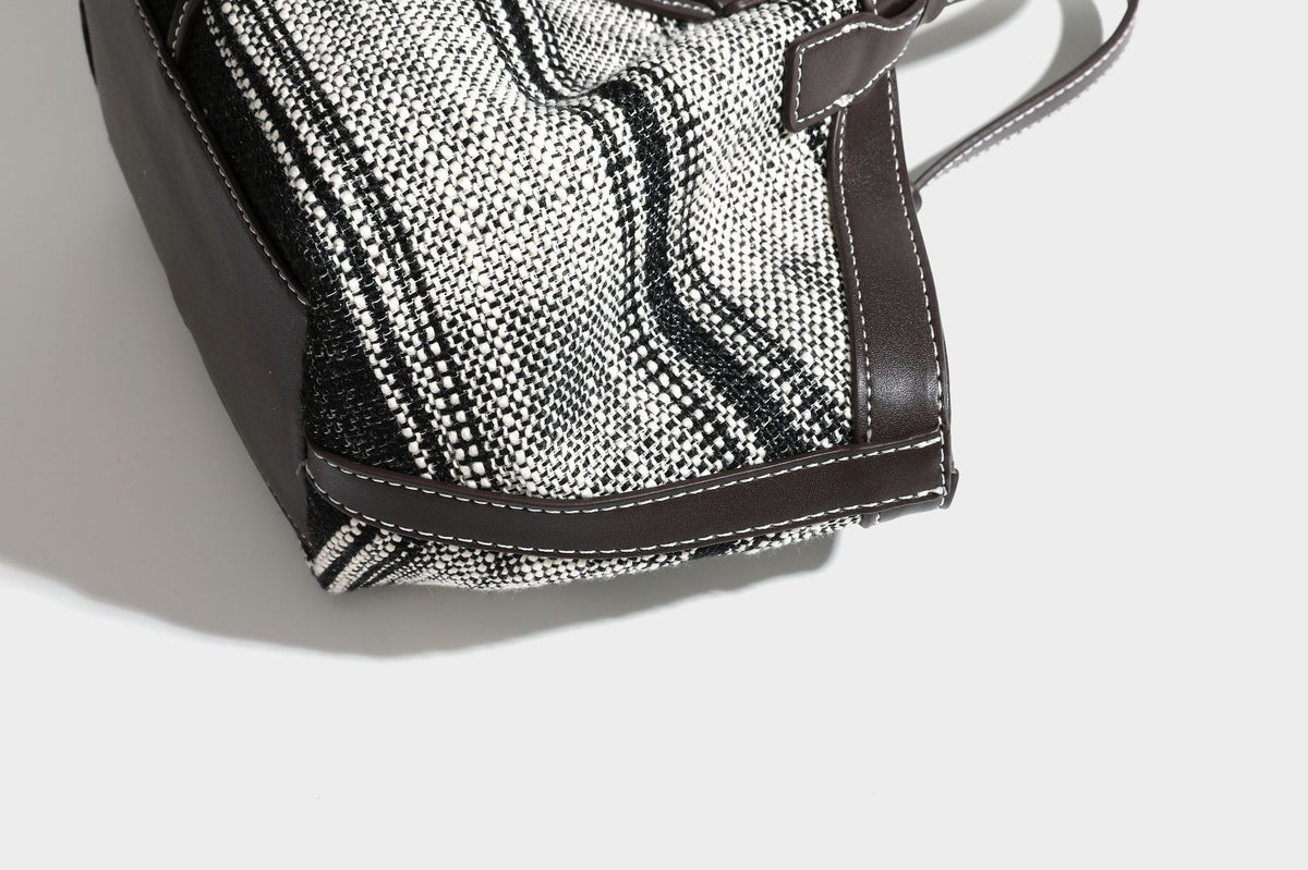 Schwarz-weiße gewebte Trapez-Tote-Bag mit dunklem Lederimitat-Besatz, weißen Kontrastnähten und zwei Henkeln, Detailansicht