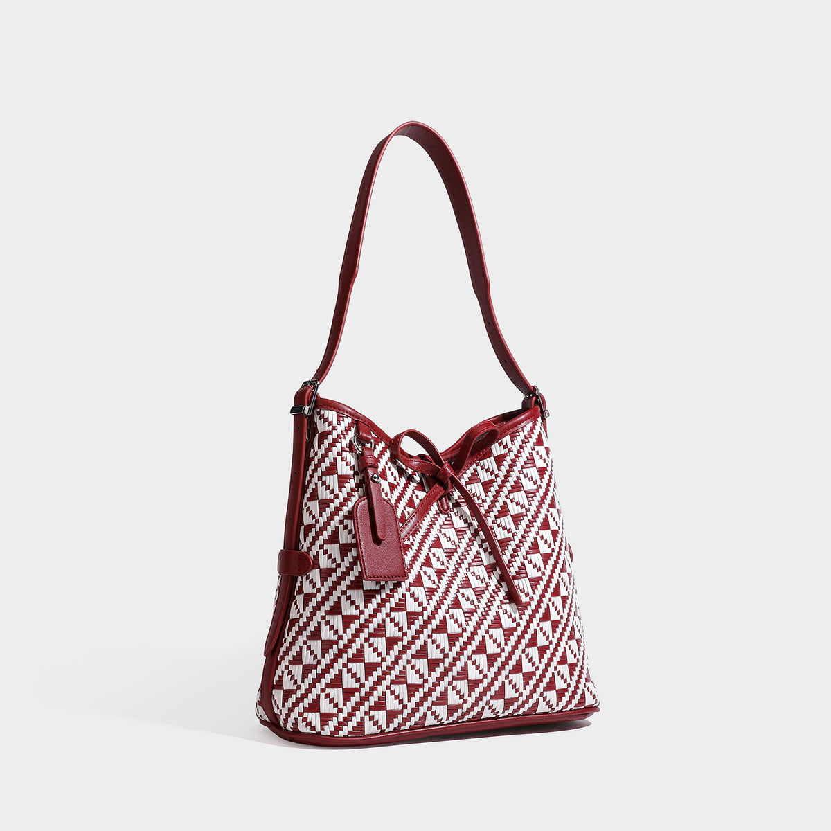 Woven geometric bucket shoulder bag in white and dark brown two-tone pattern with leather-look trim and drawstring top