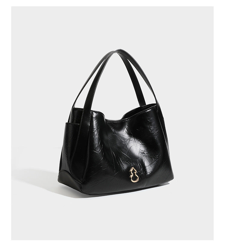 Black glossy crinkled leather-look convertible shoulder tote bag with gold gourd-shaped emblem hardware and detachable