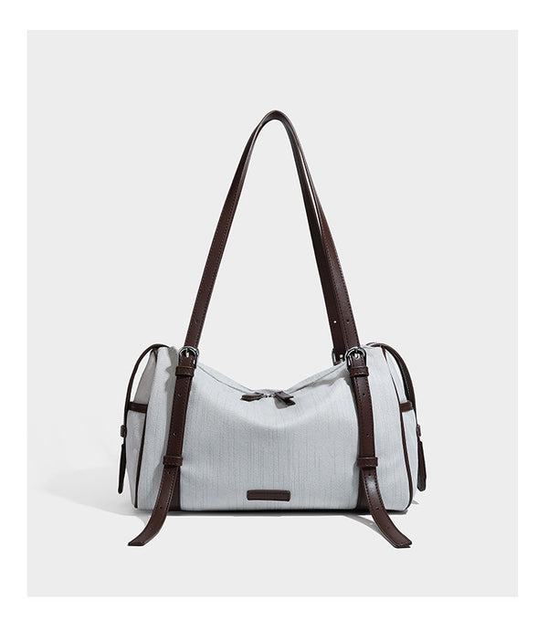 Olivgrüne Schultertasche in Zylinderform aus Canvas mit Riemen in schwarzer Lederoptik, Reißverschluss oben und silberfarbenen Beschlägen, Detailansicht