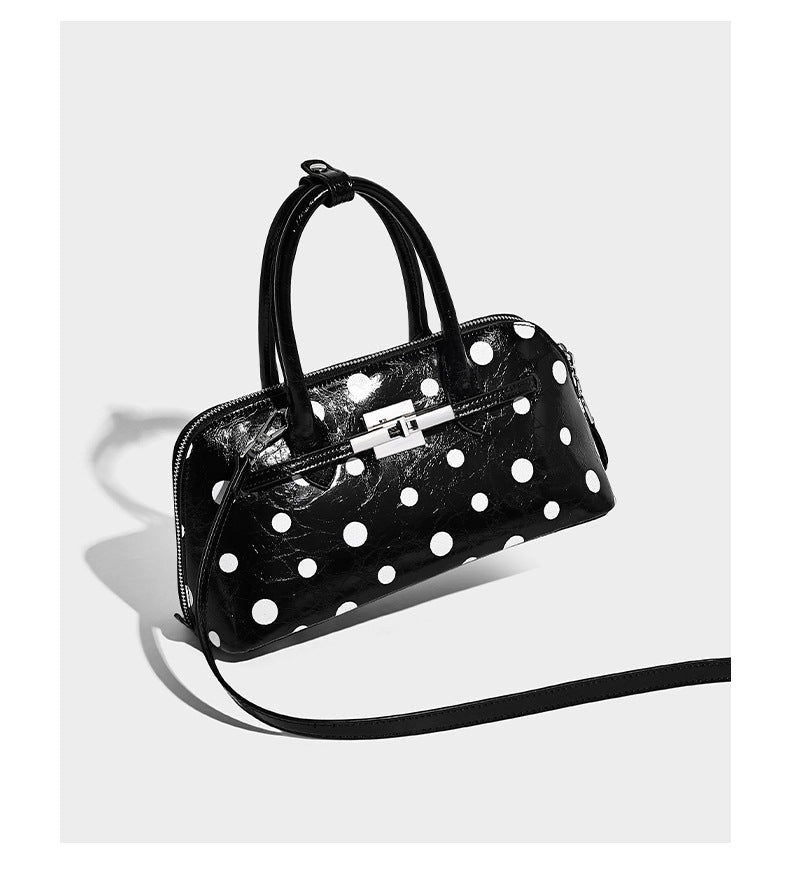 Structured polka-dot Boston bag with glossy crinkled finish, dual top handles, silver-tone turn-lock clasp, and detachable