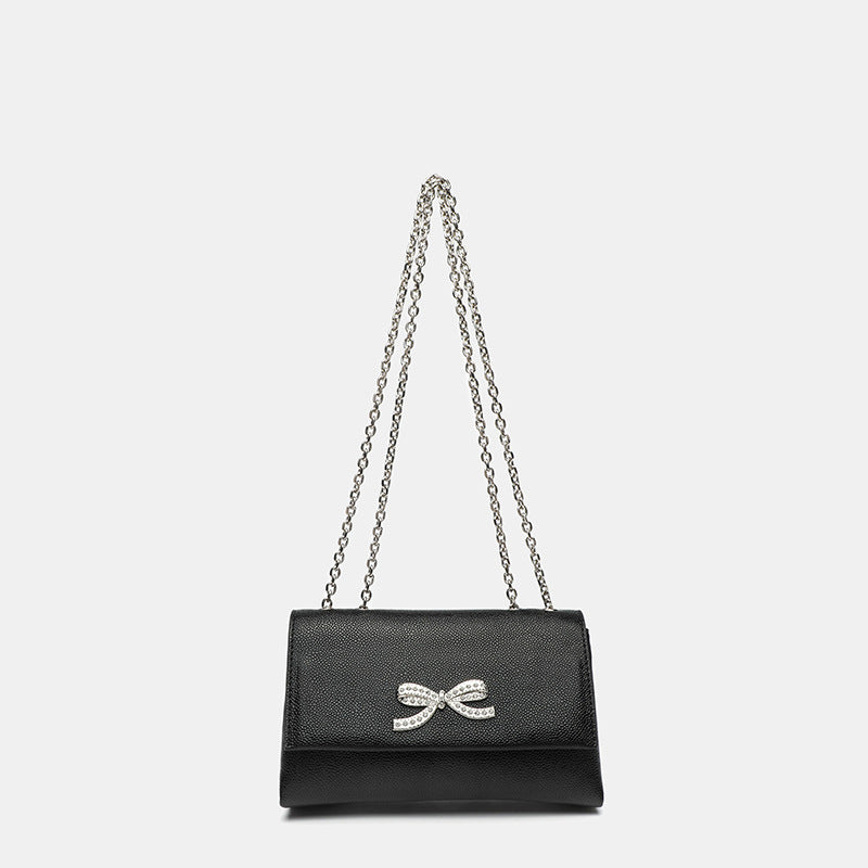 Structured rectangular flap crossbody bag with rhinestone bow and silver chain strap in pebbled finish, detail view 6