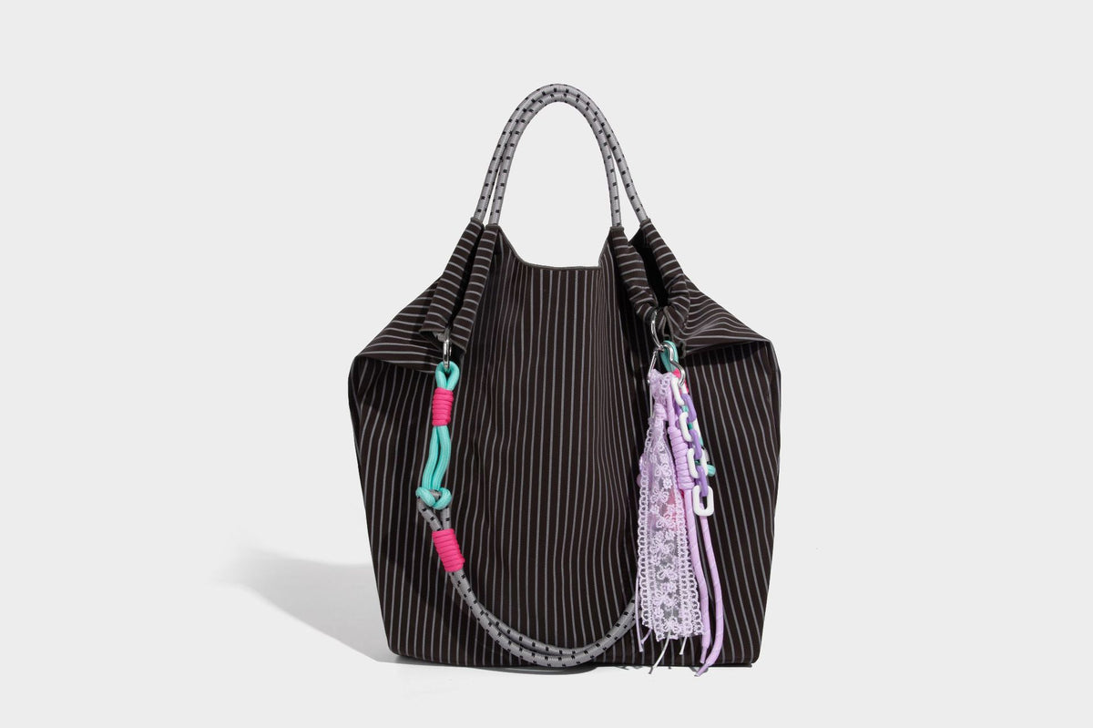 Slouchy pinstripe tote bag with braided rope handles, metal ring hardware, and colorful knotted rope charm, detail view 32