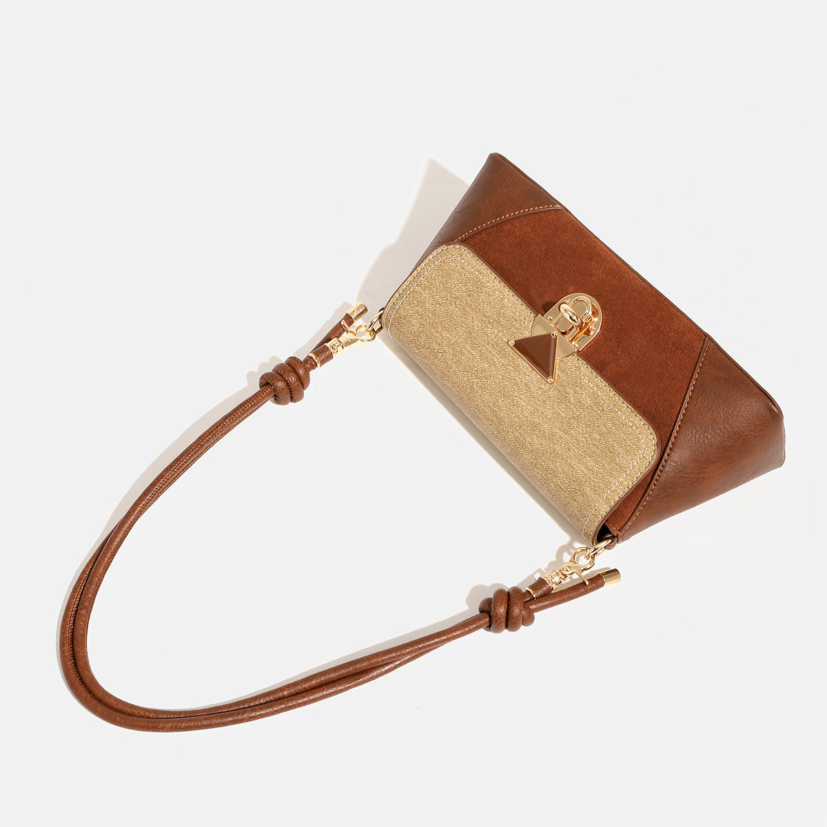 Structured trapezoid shoulder bag with pale textured flap, gold-tone triangular turn-lock closure, and long knotted cord