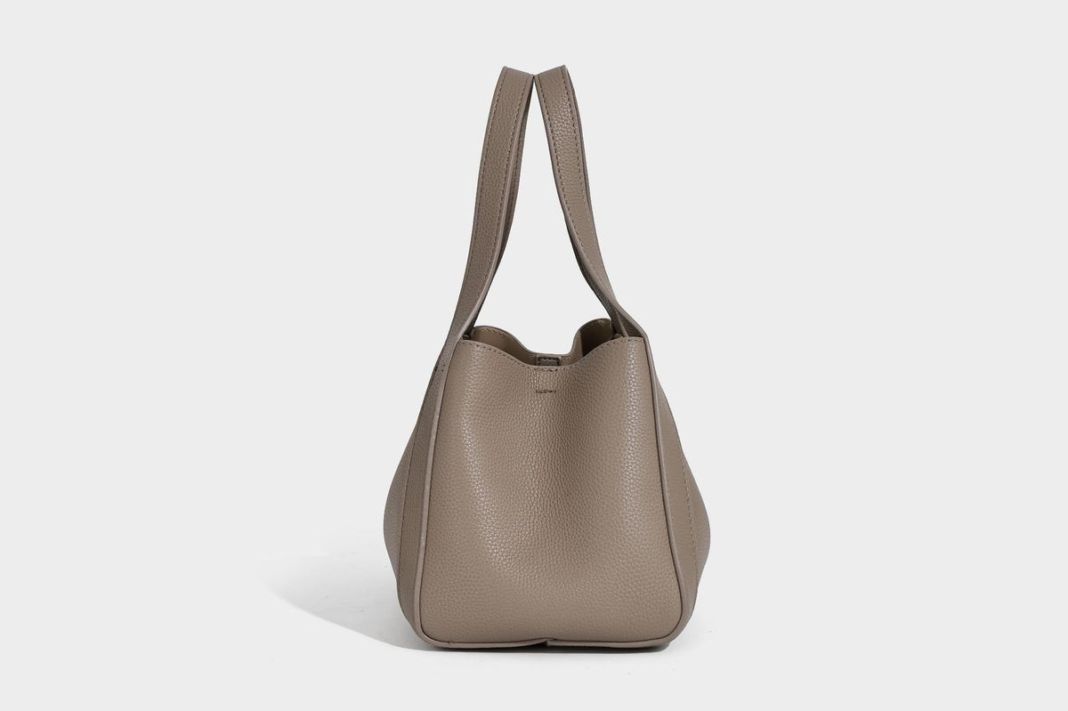 Structured trapezoid tote bag in taupe pebbled leather-look finish with gold-tone turn-lock hardware, dual top handles, and