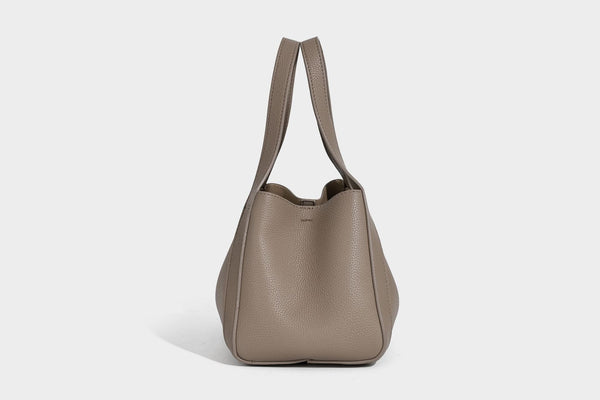 Structured trapezoid tote bag in taupe pebbled leather-look finish with gold-tone turn-lock hardware, dual top handles, and