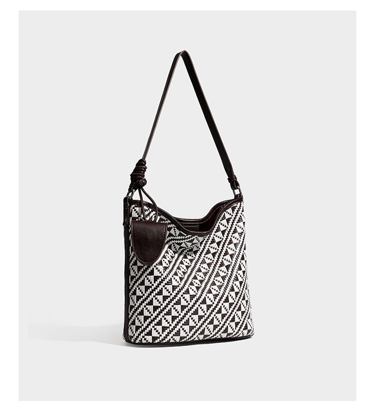 Geflochtene Schultertasche mit geometrischem Ethno-Muster, Besatz in dunkelbrauner Lederoptik, langem verstellbarem Träger und kleinem hängendem Reißverschluss