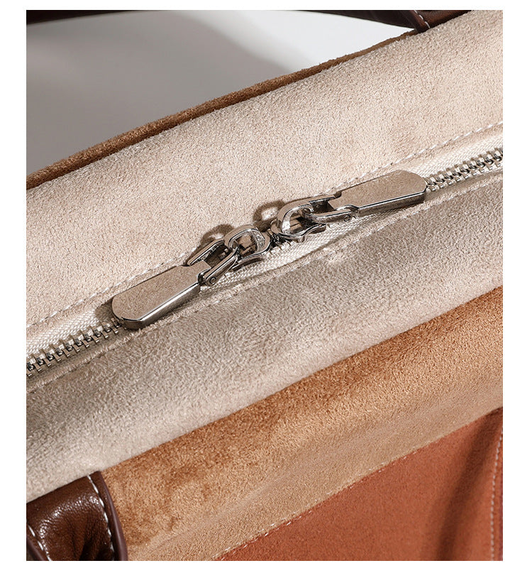 Boxy patchwork suede-look shoulder tote in tan, beige, rust, and brown panels with double brown straps and hanging doll