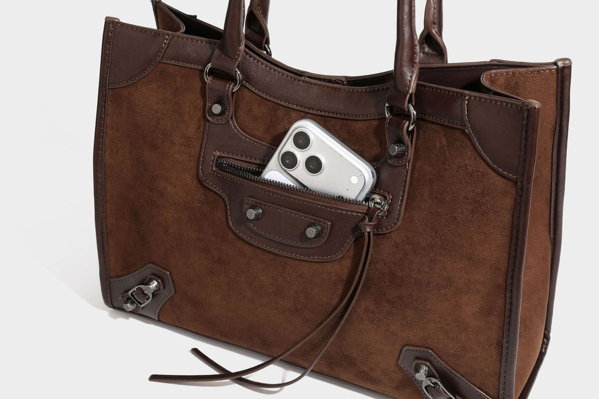 Large structured tote bag with matte suede-like body, smooth leather-look trim, front zip pocket, stud hardware, and