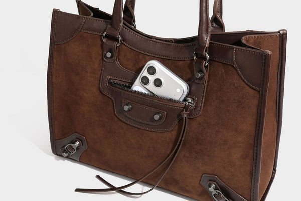 Large structured tote bag with matte suede-like body, smooth leather-look trim, front zip pocket, stud hardware, and