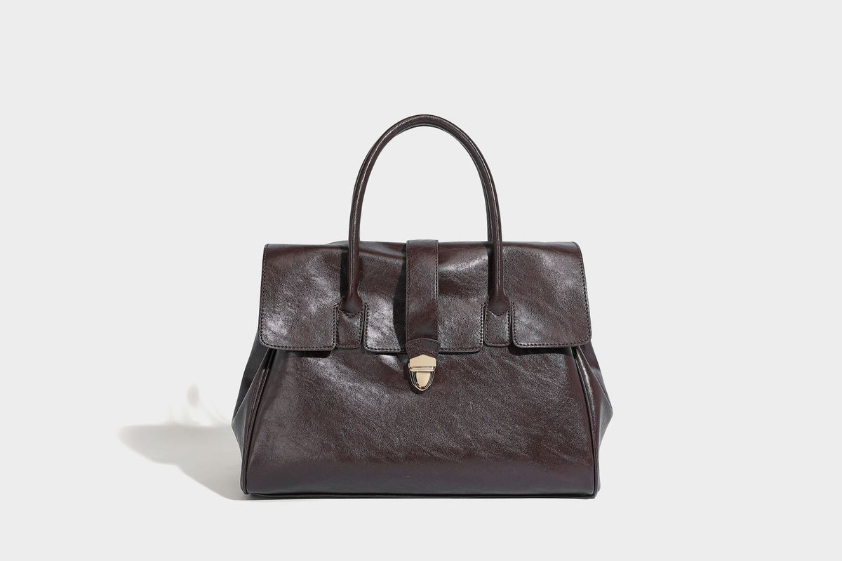 Strukturierte Henkeltasche in glänzender Lederoptik mit Überschlagverschluss, mittigem Riemen, goldfarbenem Drehverschluss und zwei Henkeln