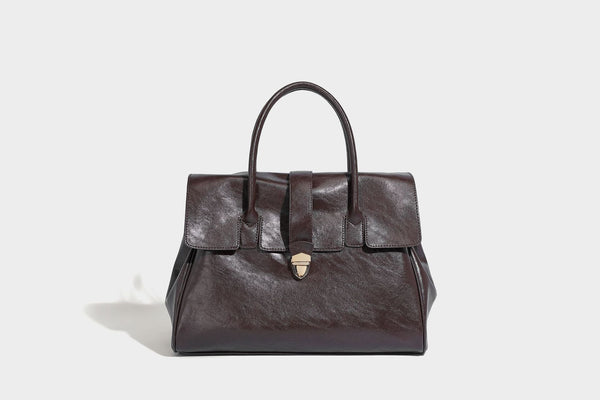 Strukturierte Henkeltasche in glänzender Lederoptik mit Überschlagverschluss, mittigem Riemen, goldfarbenem Drehverschluss und zwei Henkeln