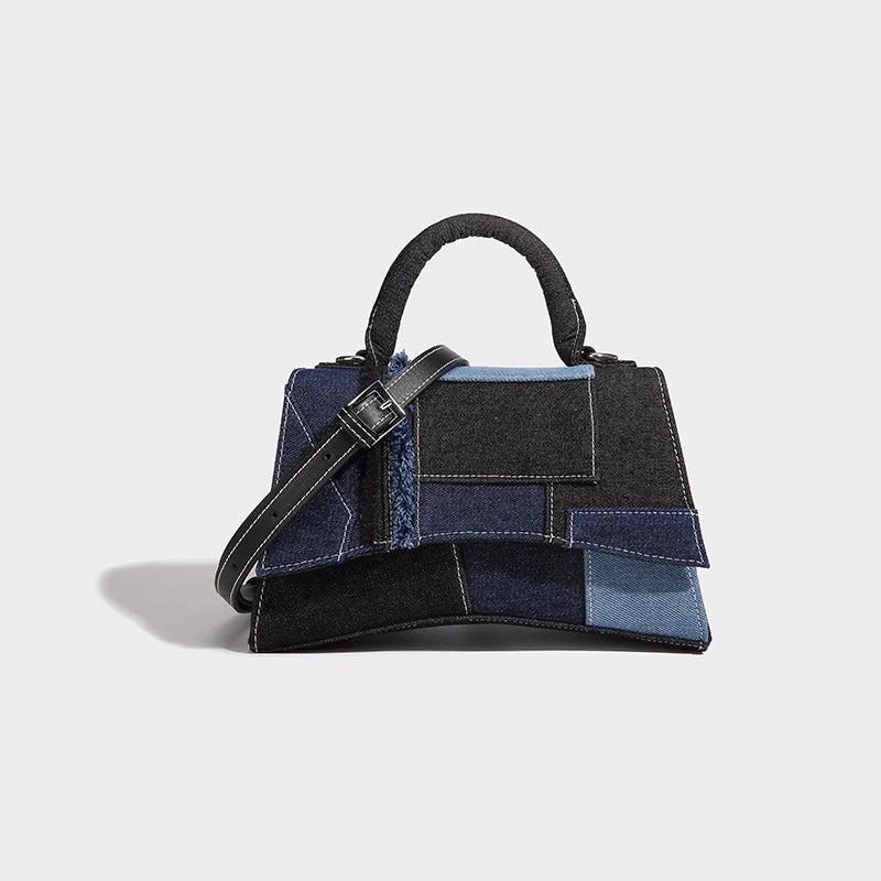 Structured patchwork denim trapezoid satchel bag with frayed panel trim, rounded top handle, and silver-tone hardware, detail