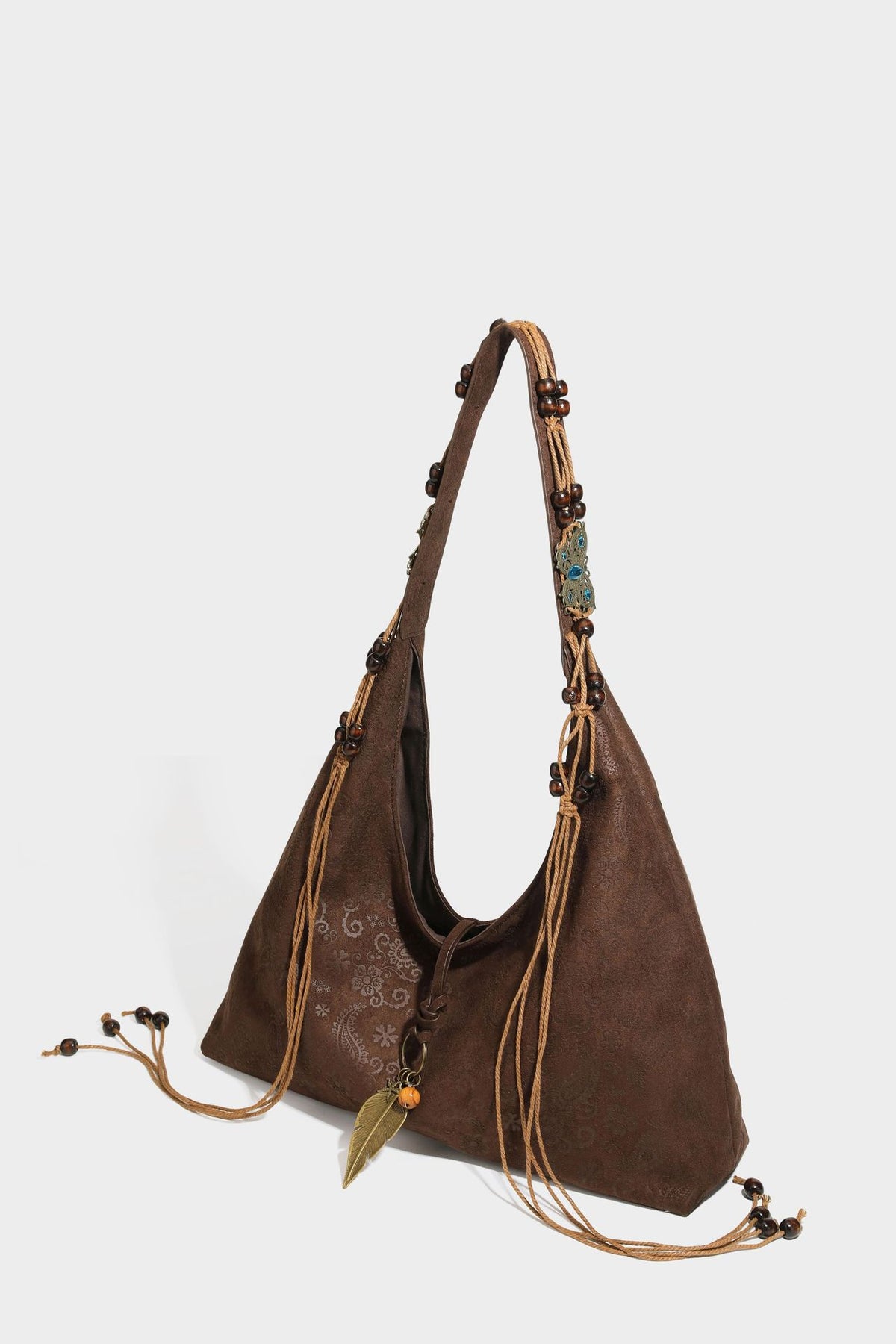 Slouchy boho hobo shoulder bag in embossed brown suede-look finish with beaded strap, cord tassels, and brass-tone leaf