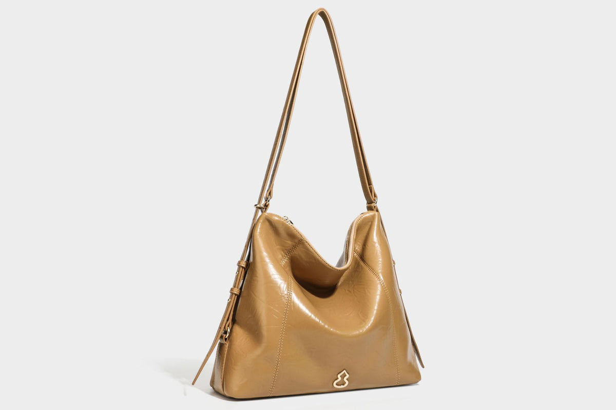 Große, lässig fallende Hobo-Schultertasche in glänzender, geknautschter Lederoptik mit goldfarbenen Beschlägen und langem, verstellbarem Riemen