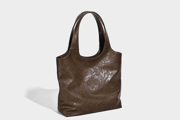 Large open-top tote bag with crinkled leather-look finish, long double shoulder straps, and embossed circular detail on