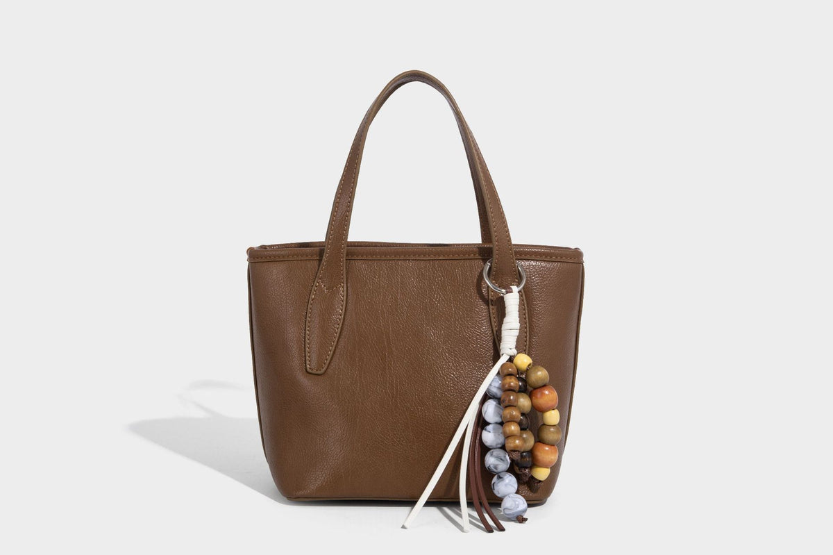 Compact structured bucket tote bag with pebbled textured finish, dual top handles, silver-tone lock hardware, and detachable