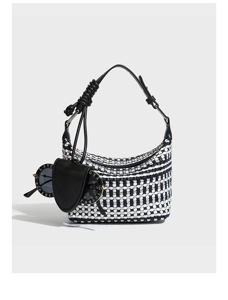 Small crescent shoulder bag in black-and-white woven textile with smooth black leather-look trim, zip-top closure, knotted