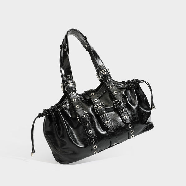 Large black glossy leather-look tote bag with silver buckle straps, eyelet grommet panels, drawstring side gathers, and