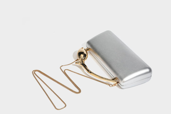 Strukturierte rechteckige Clutch mit goldfarbenem Henkel in Form einer Rosenknospe und abnehmbarem Kettenriemen in Metallic-Optik, Detailansicht