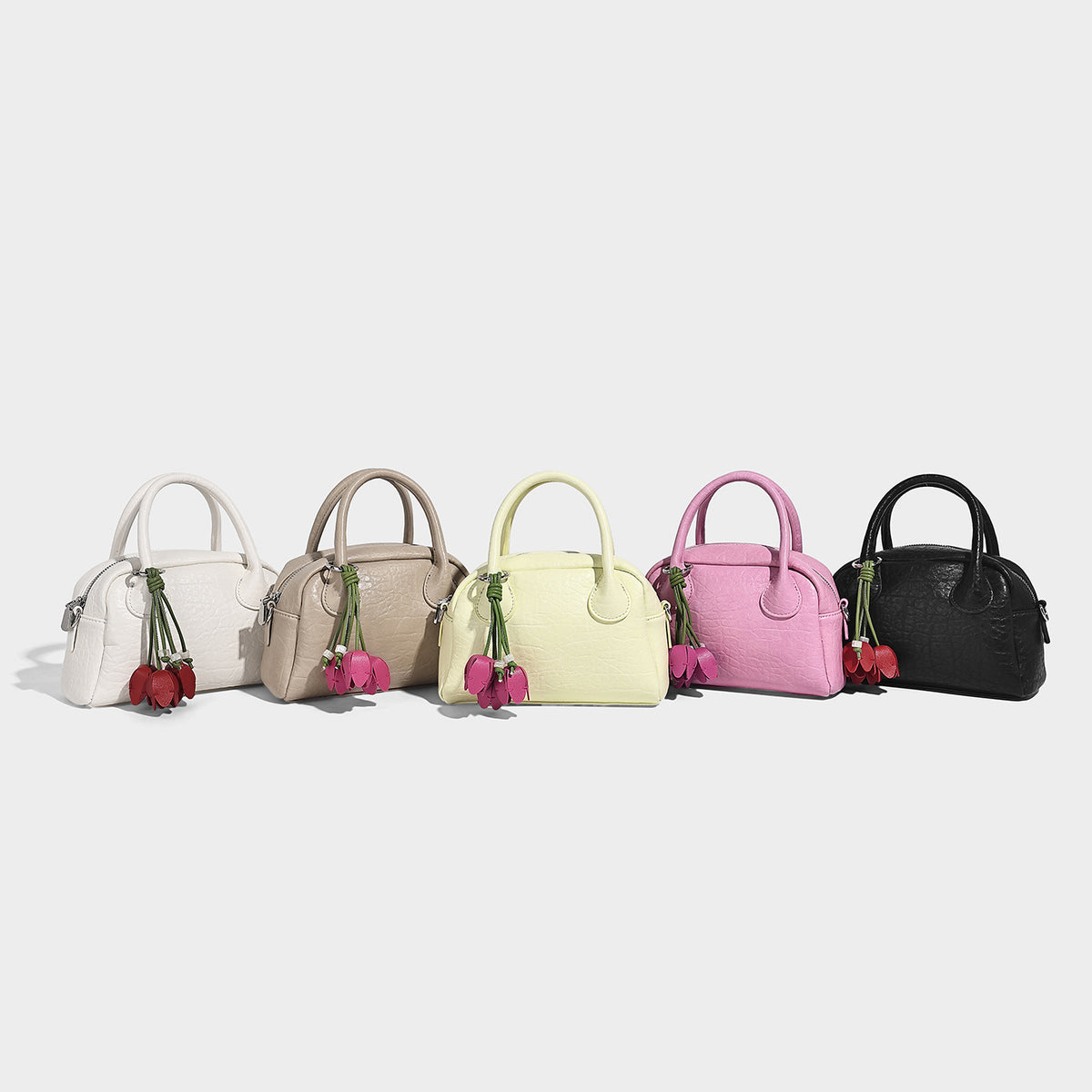 Mini structured dome top-handle bag in pastel yellow with pebbled leather-look finish, silver-tone hardware, and detachable