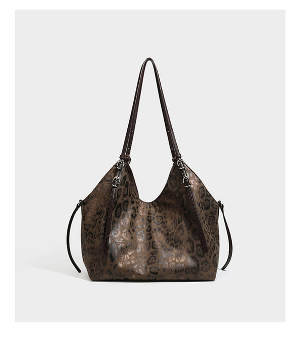 Slouchy leopard-print shoulder tote bag in tan and brown with long double straps, side tie straps, and dangling charm, detail