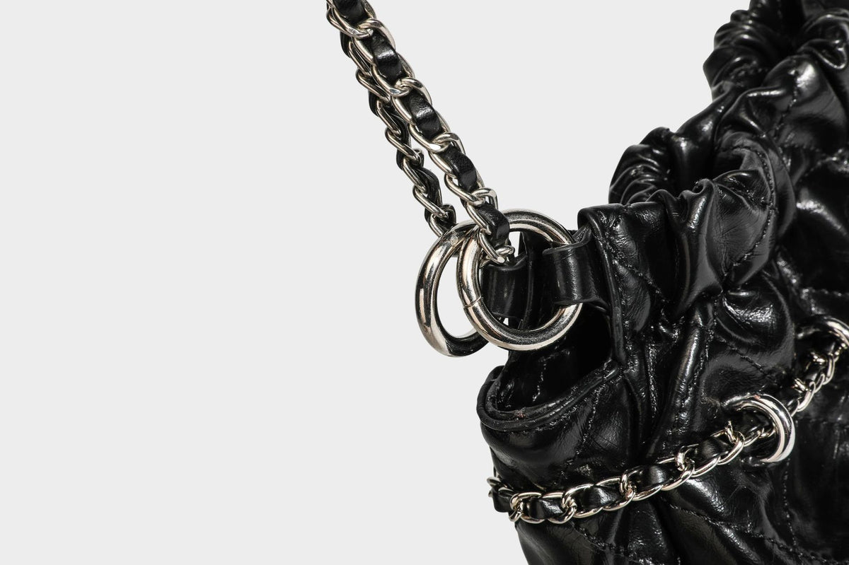 Glossy diamond-quilted drawstring bucket bag with silver chain shoulder strap and medallion charm, detail view 32