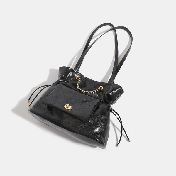 Black glossy diamond-quilted bucket tote bag with gold-tone chain accent, turn-lock front flap pocket, drawstring side ties
