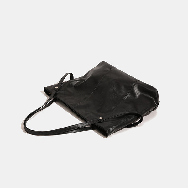 Große quadratische Shopper-Tasche in schwarzer Lederoptik mit zwei Schultergriffen und längerem Trageriemen, glatte glänzende Oberfläche und seitliche Beschläge