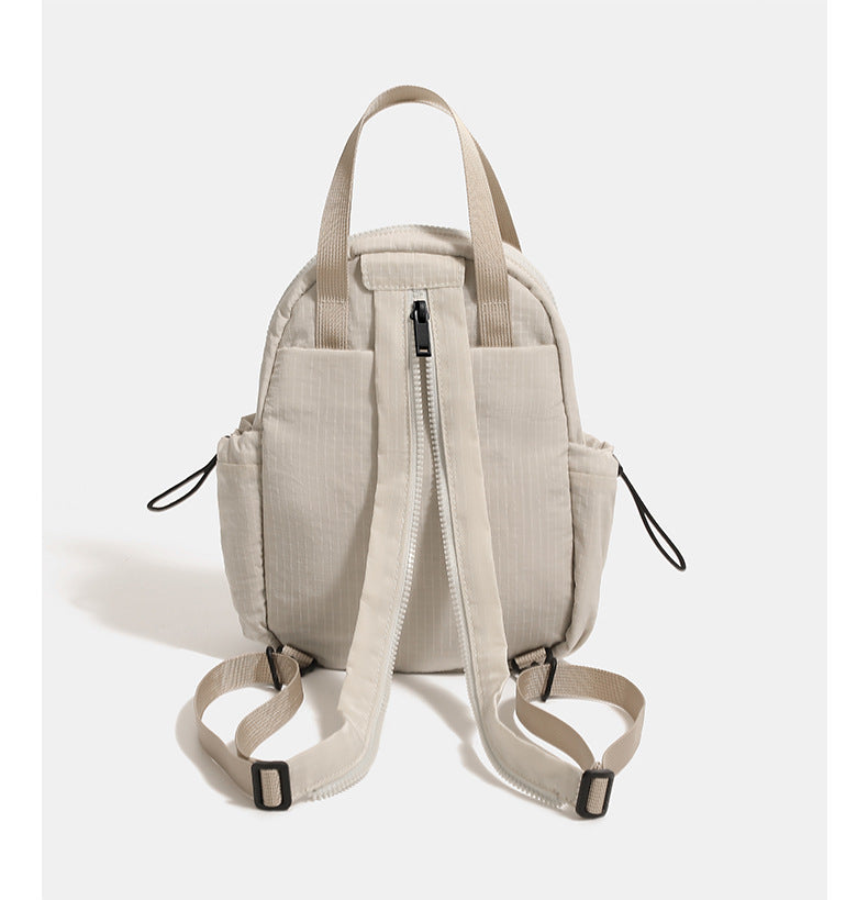 Mini rounded convertible backpack handbag in matte ripstop fabric with dual top handles, adjustable straps, and side, detail