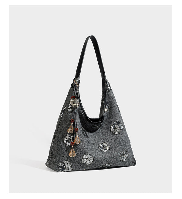 Lässig fallende, trapezförmige Schulter-Tote in Anthrazitgrau mit floralen Paillettenmotiven in Silber, Riemen in Lederoptik und herabhängendem Perlenbesatz