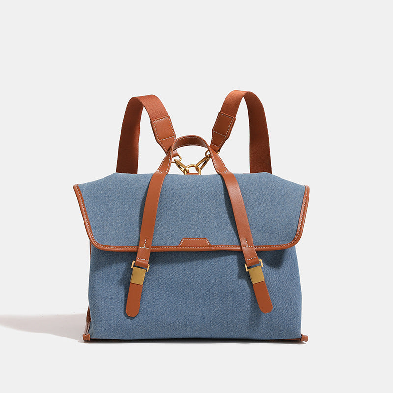 Structured denim-look convertible backpack handbag with cognac leather-look trim, gold-tone buckle hardware, and top carry