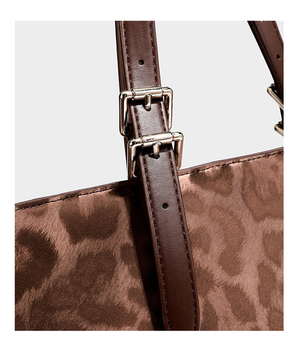 Glossy leopard-print tote bag with leather-look dark trim, dual top handles, detachable shoulder strap, and attached front