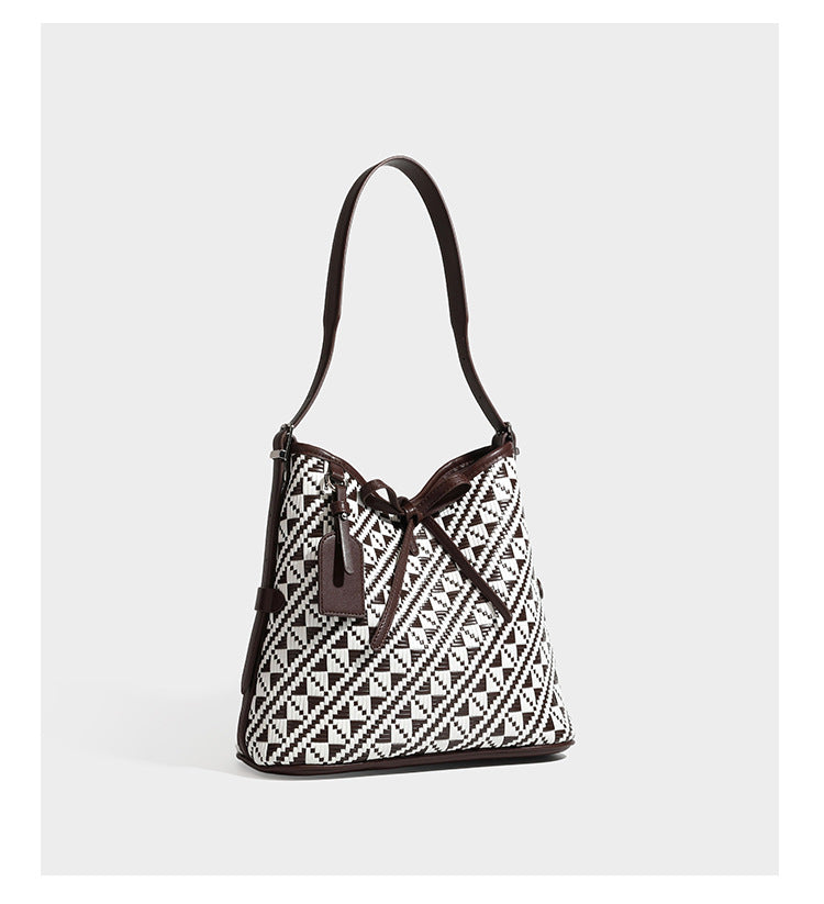 Woven geometric bucket shoulder bag in white and dark brown two-tone pattern with leather-look trim and drawstring top