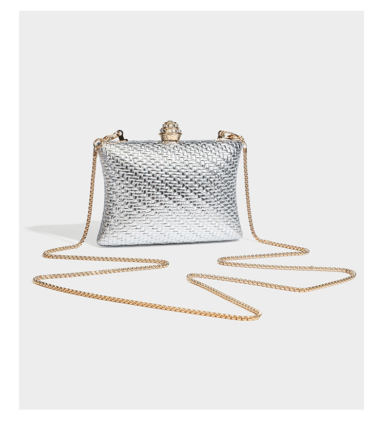 Small structured rectangular metallic woven-texture clutch bag with jeweled knob clasp and gold-tone chain strap, detail view