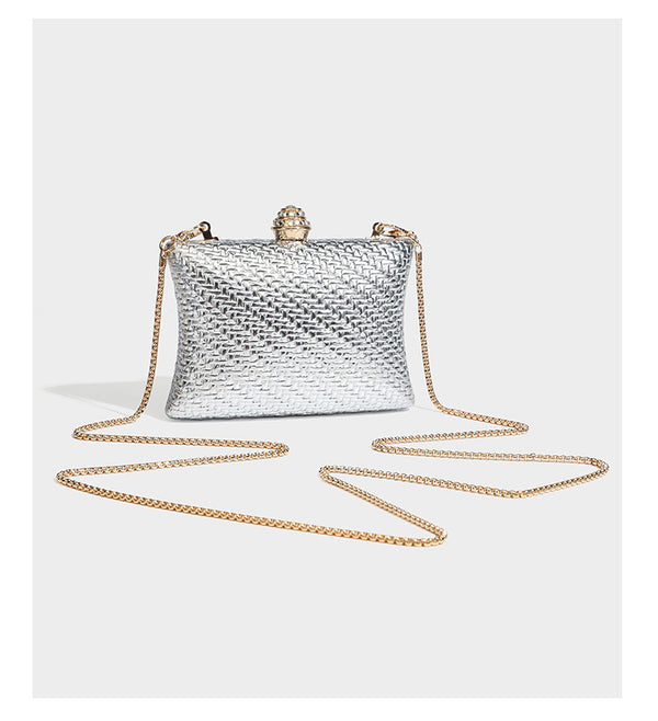 Small structured rectangular metallic woven-texture clutch bag with jeweled knob clasp and gold-tone chain strap, detail view