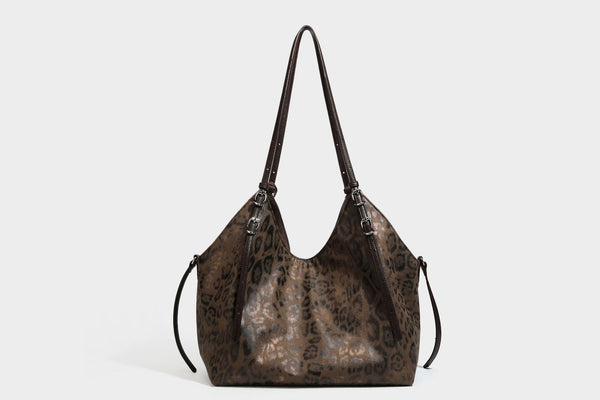 Slouchy leopard-print shoulder tote bag in tan and brown with long double straps, side tie straps, and dangling charm, detail