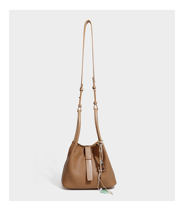 Pebbled leather-look bucket tote bag with rolled double handles, drawstring closure, braided cord charm, and detachable