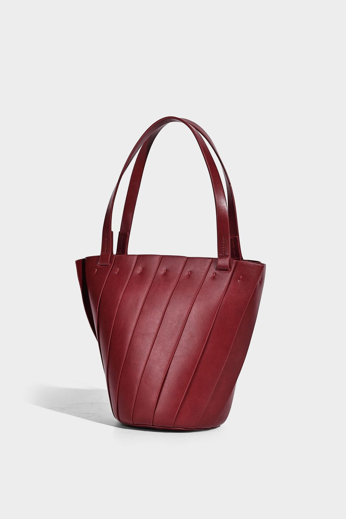 Structured bucket tote bag with vertical panel exterior, dual top handles, and detachable shoulder strap in tan leather-look
