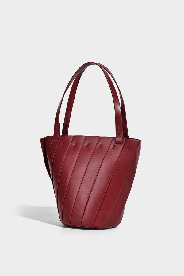 Structured bucket tote bag with vertical panel exterior, dual top handles, and detachable shoulder strap in tan leather-look