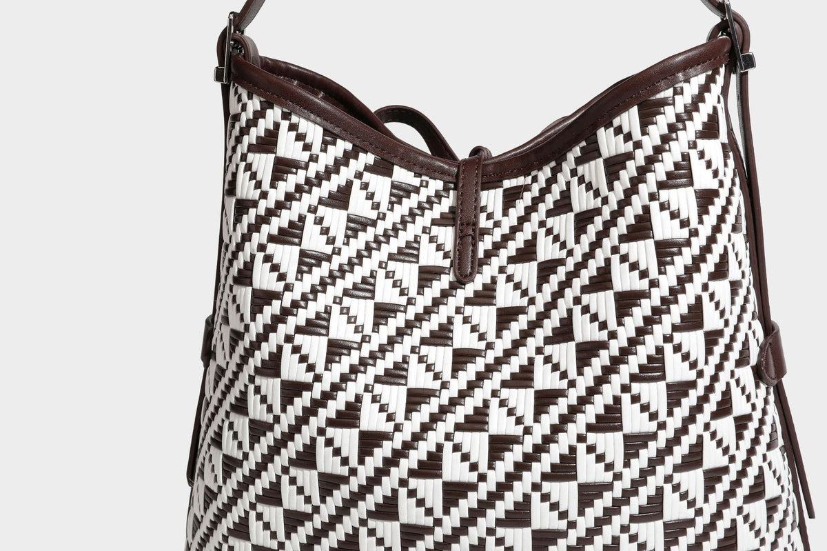 Woven geometric bucket shoulder bag in white and dark brown two-tone pattern with leather-look trim and drawstring top